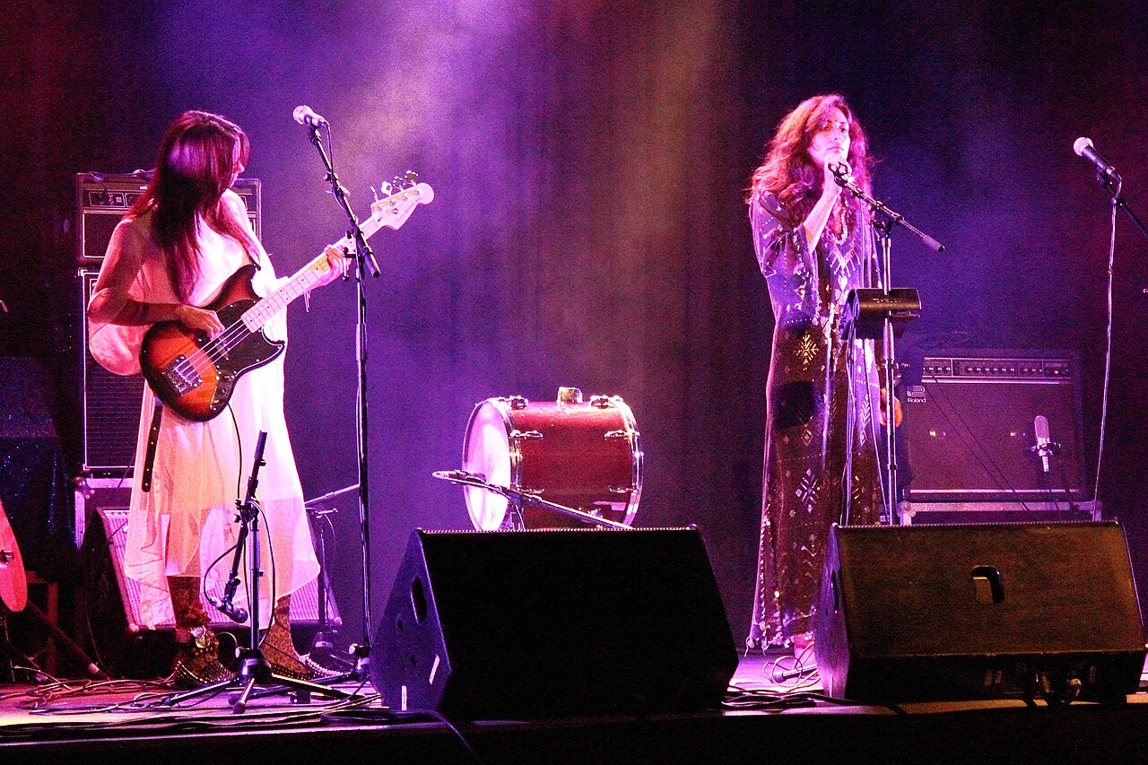 Η Yasmine Hamdan τραγουδά σε μικρόφωνο με μπασίστ στην αριστερή πλευρά και μοβ φωτισμό· φωτογραφία αρχείου του 2013, όχι του Borderline 2026.