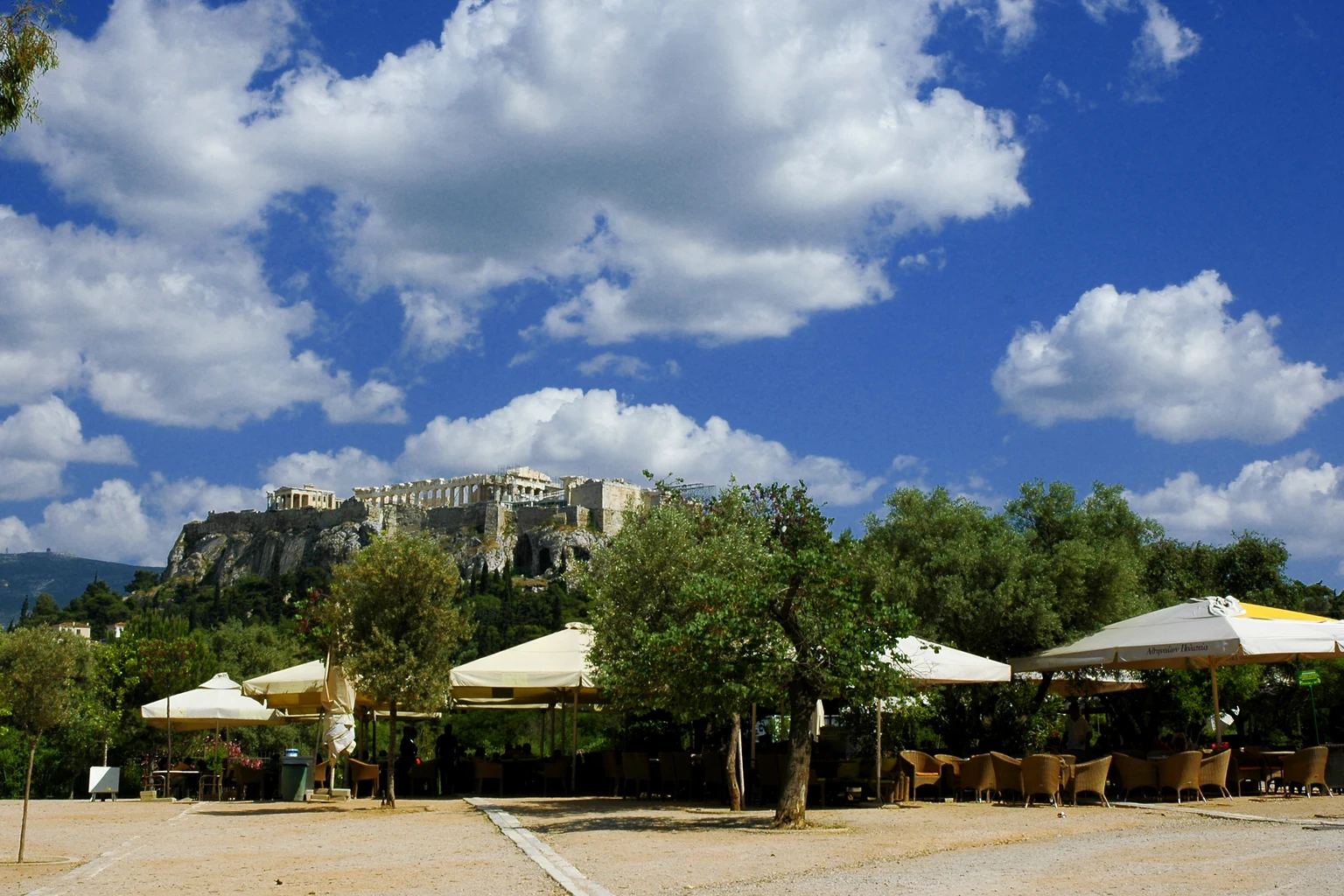 Τραπεζοκαθίσματα και ομπρέλες υπαίθριου καφέ στην Αθήνα, με την Ακρόπολη στο βάθος, σε φωτογραφία αρχείου του 2012.
