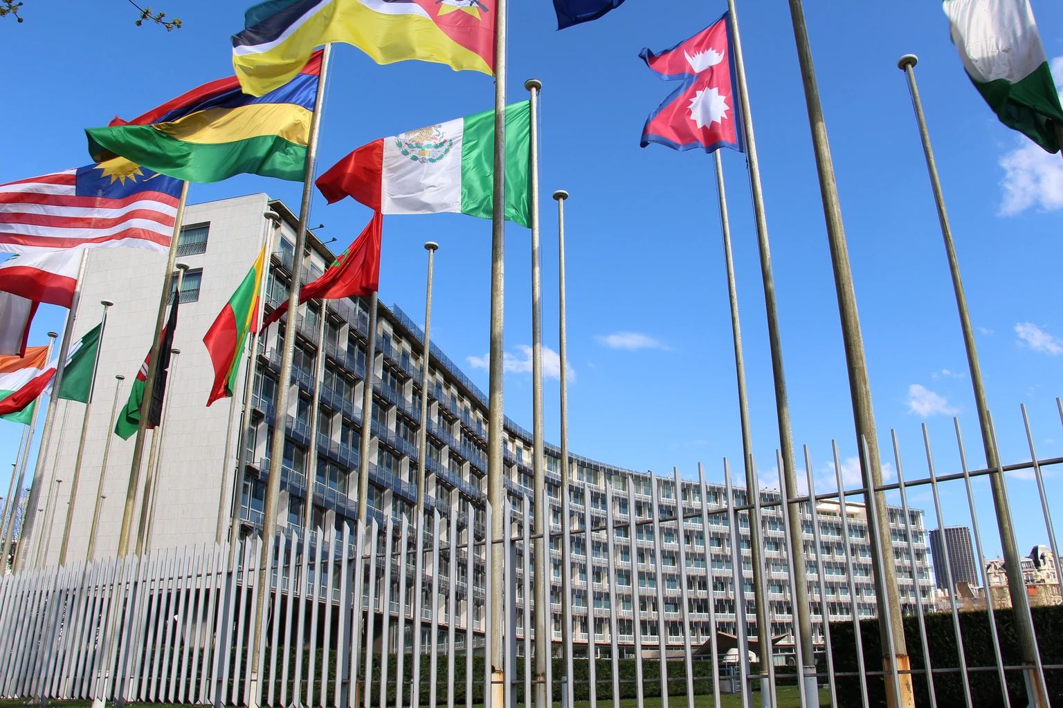 Αρχειακή φωτογραφία του κτιρίου της UNESCO στο Παρίσι με σημαίες και μεταλλικό φράκτη, χωρίς αναγνωρίσιμους ανθρώπους.