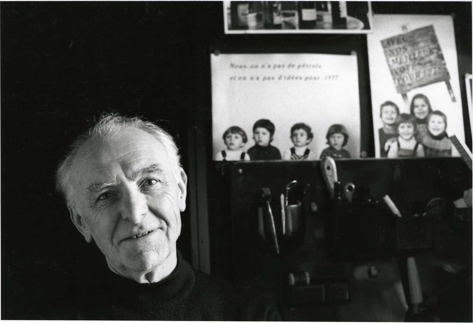 Ασπρόμαυρη φωτογραφία αρχείου του Robert Doisneau στο εργαστήριό του στο Montrouge, το 1992, με φωτογραφίες στο φόντο.