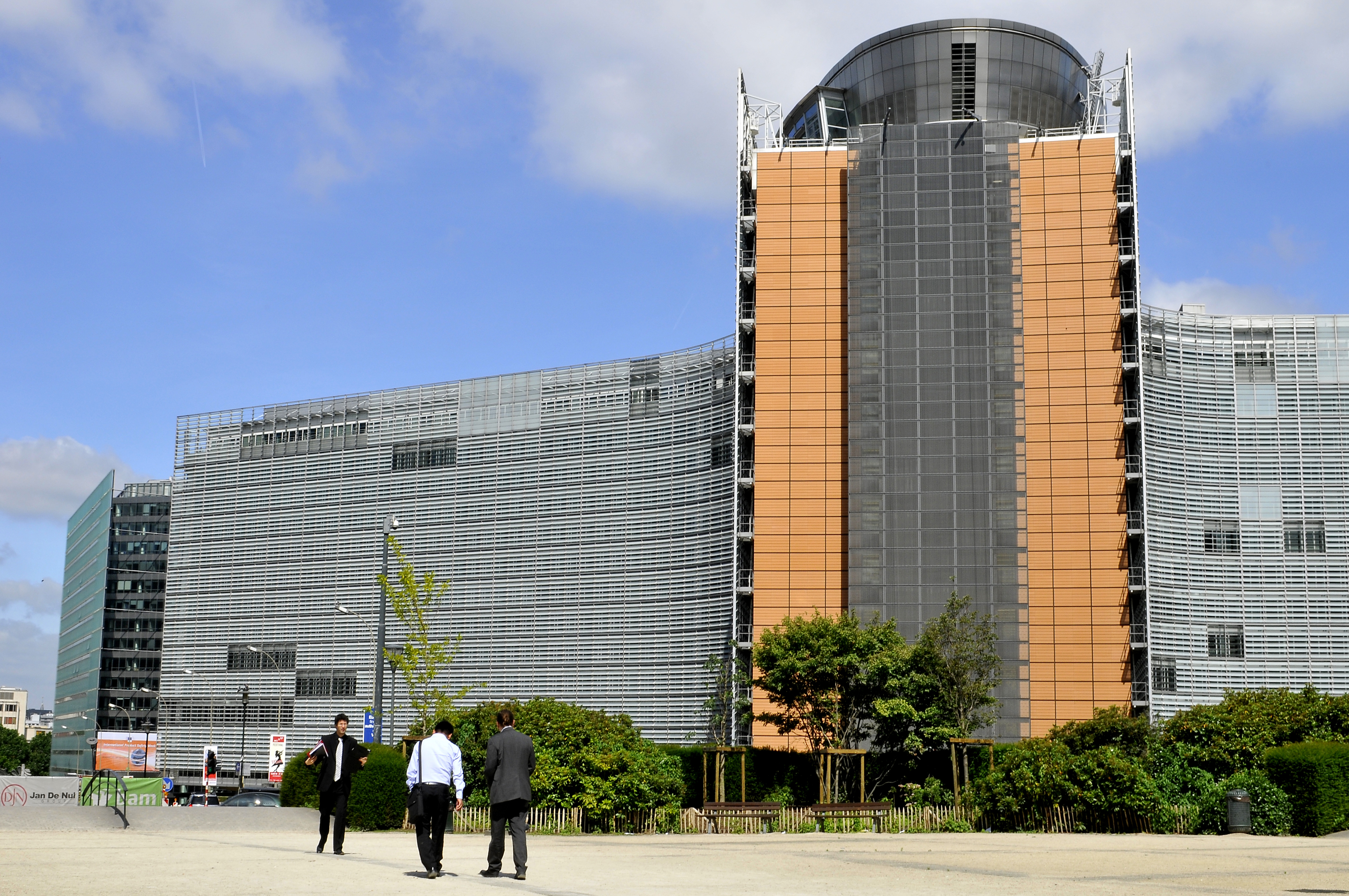 Πρόσοψη του Berlaymont στις Βρυξέλλες, με δρόμο, μικρές πινακίδες και περαστικούς μπροστά· πραγματική φωτογραφία αρχείου του 2014.
