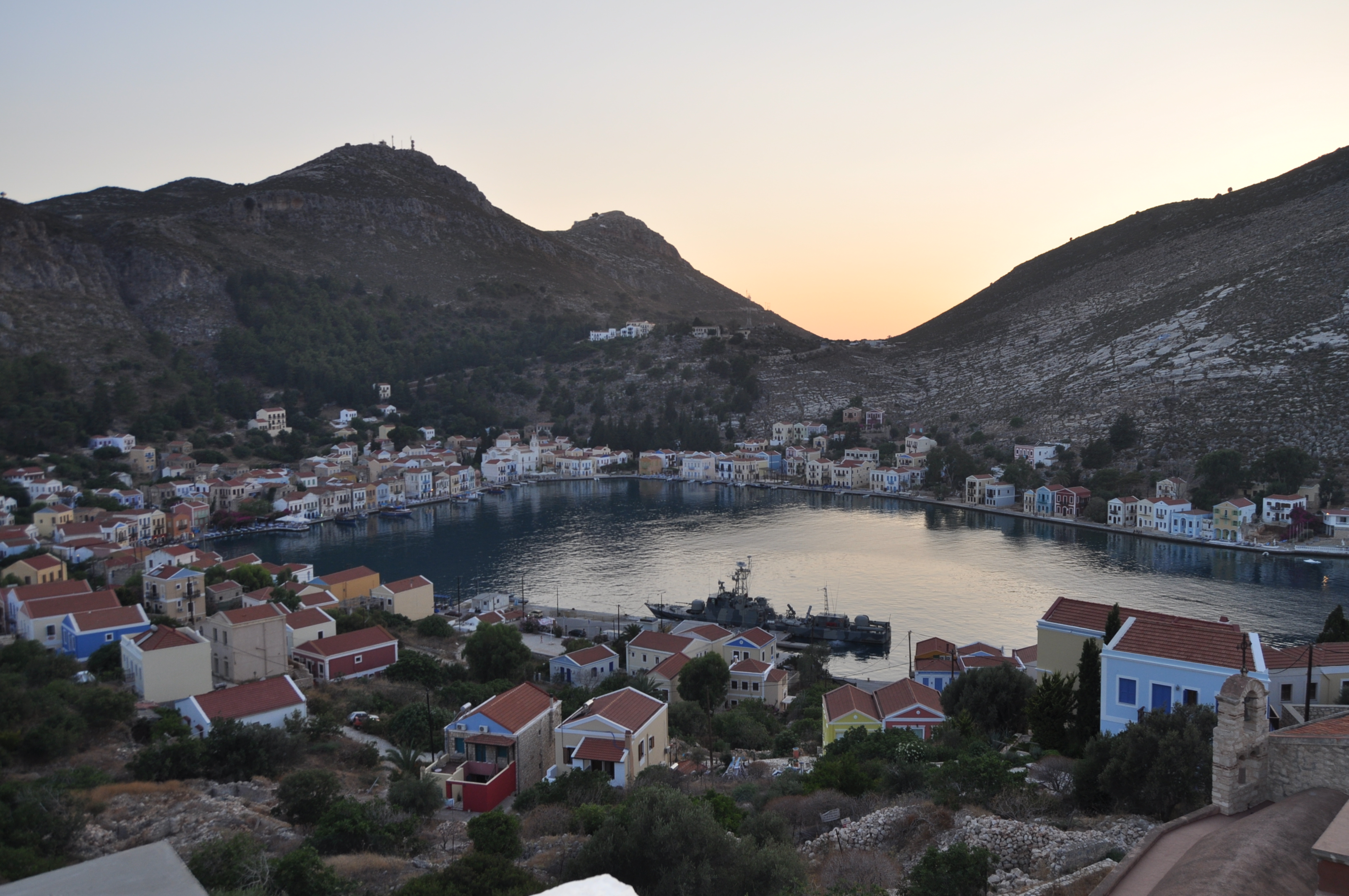 Λιμάνι με πολύχρωμα σπίτια, βραχώδεις λόφους και ένα σκάφος στο Καστελλόριζο, σε φως δειλινού· φωτογραφία αρχείου 2017, όχι της εκδήλωσης.